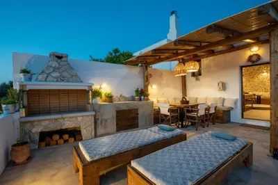a patio with two beds and a fireplace at Mareò Traditional Retreat in Archangelos