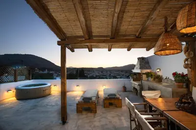 a patio with a table and chairs and a hot tub at Mareò Traditional Retreat in Archangelos