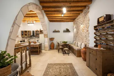 a large room with a stone wall and a table and chairs at Mareò Traditional Retreat in Archangelos
