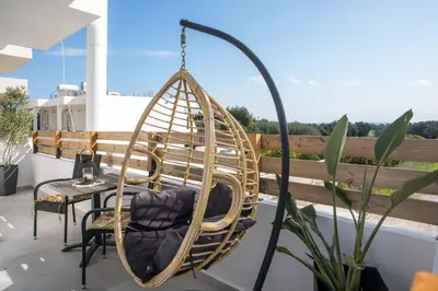 a swing chair on a balcony with a table at Olea Luxury Apartment in Afantou