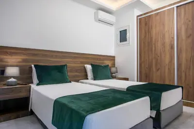 two beds in a bedroom with green and white at Olea Luxury Apartment in Afantou
