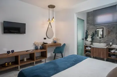 a bedroom with a bed and a desk and a mirror at Olea Luxury Apartment in Afantou