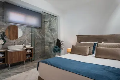 a bathroom with a bed and a shower and a sink at Olea Luxury Apartment in Afantou