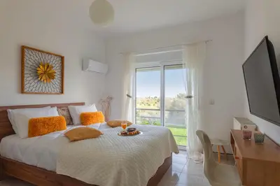 a bedroom with a bed with a table and a window at abk apartment in Afantou