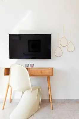 a white chair and a television on a wall at abk apartment in Afantou