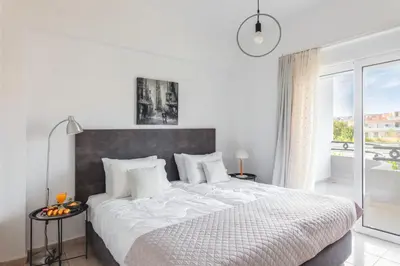 a white bedroom with a large bed and a window at abk apartment in Afantou