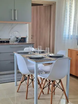 a dining room table with white chairs in a kitchen at Dionysia apartments in Livadia