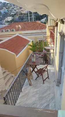a balcony with a table and chairs on a building at Evangelia in Symi