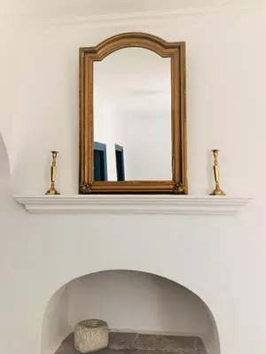a mirror on a wall above a fireplace at Evangelia in Symi