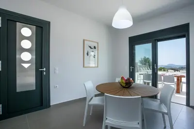 a dining room with a wooden table and white chairs at Villa Aurora in Faliraki