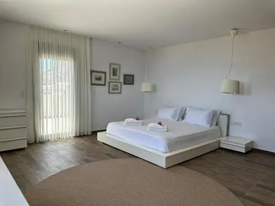 a white bedroom with a large white bed and a window at Solis Lindos Villa in Líndos
