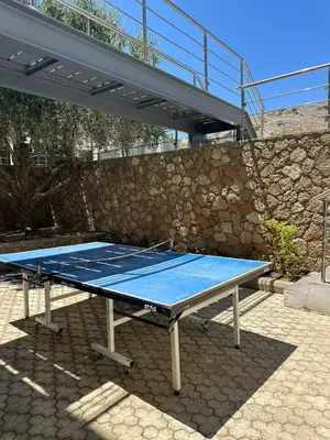 a blue ping pong table in front of a stone wall at Solis Lindos Villa in Líndos