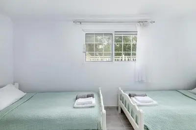 two beds in a white room with a window at Beach House Cavo Kiotari in Gennadi