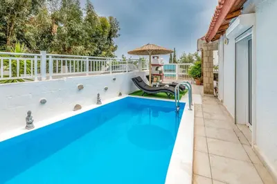 a swimming pool with a chair next to a house at Beach House Cavo Kiotari in Gennadi