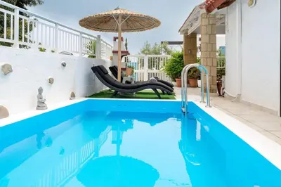 a pool with a slide and an umbrella at Beach House Cavo Kiotari in Gennadi
