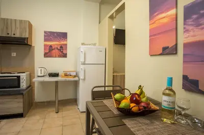 a kitchen with a table with a bowl of fruit and a bottle of wine at Irinis studio in Rhodes Town