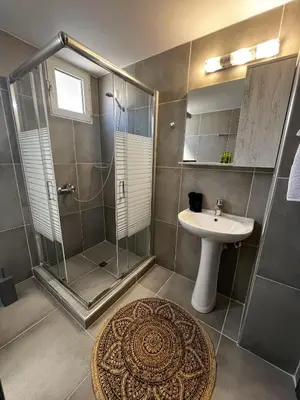 a bathroom with a glass shower and a sink at Maquestas Modern Apartments in Archangelos