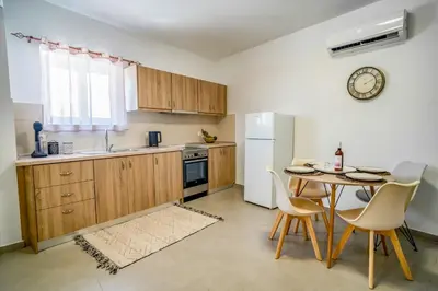a kitchen with a table and a white refrigerator at Maquestas Modern Apartments in Archangelos