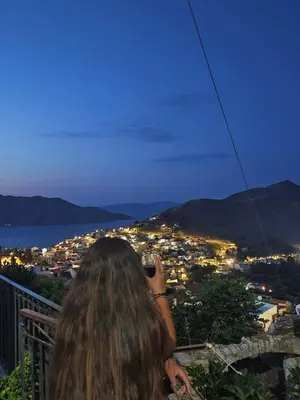 a woman taking a picture of a city at night at Aelia studio in Symi