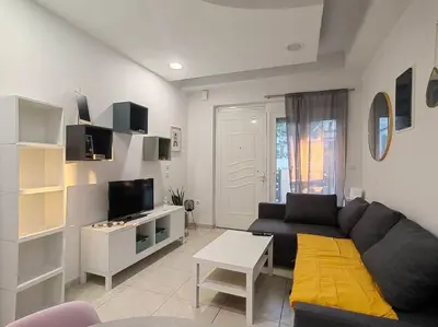 a living room with a black couch and a tv at The Cozy Nest in Rhodes town in Rhodes Town