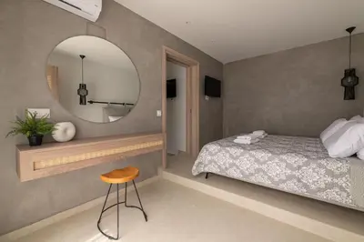 a bedroom with a bed and a mirror and a stool at Aqua Villa Faliraki in Faliraki