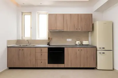 a kitchen with wooden cabinets and a refrigerator at Aqua Villa Faliraki in Faliraki