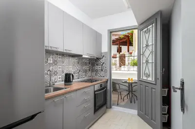 a kitchen with white cabinets and a window at FOURLANOU HOUSE in Halki