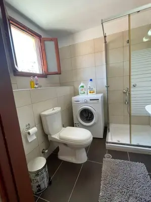 a bathroom with a toilet and a washing machine at Foteini’s House in Symi