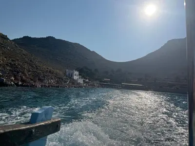 a boat in a body of water with mountains at Foteini’s House in Symi