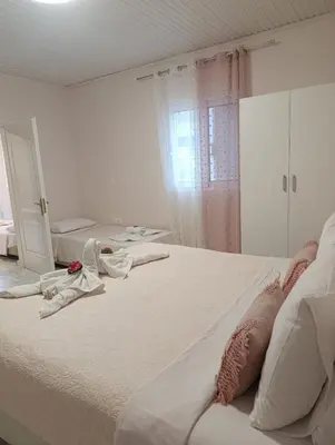 a white bedroom with two beds and a mirror at Sunny house in Kremasti