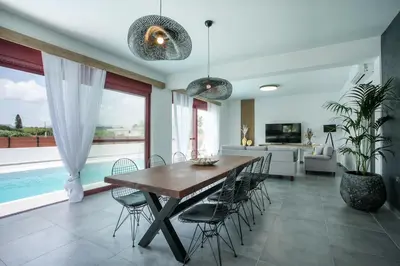 a dining room with a wooden table and chairs at SunDaLucky in Afantou