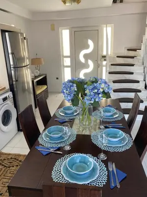 a dining table with blue plates and a vase of flowers at Sunny Garden Villa Koskinou in Koskinou