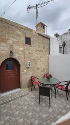 a patio with two chairs and a table and a door at Heliophilia Malona in Malona Village