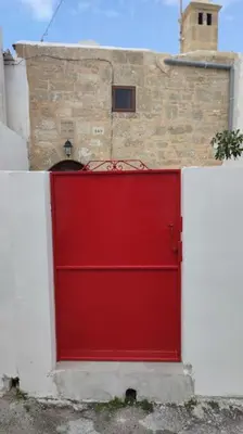 a red garage door in front of a brick building at Heliophilia Malona in Malona Village
