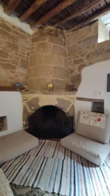 a living room with a stone fireplace and a couch at Heliophilia Malona in Malona Village