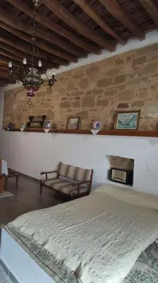 a bedroom with a bed and a stone wall at Heliophilia Malona in Malona Village