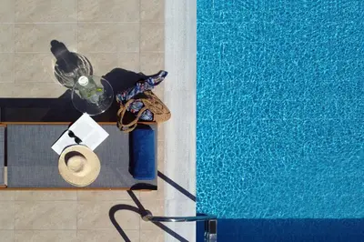 a table next to a swimming pool with a hat at Villa Arco Bianco in Afantou