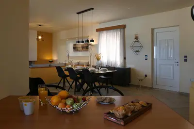 a kitchen and living room with a table with a bowl of fruit at Villa Arco Bianco in Afantou
