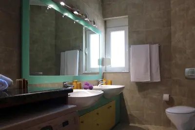 a bathroom with two sinks and a mirror and a toilet at Villa Arco Bianco in Afantou