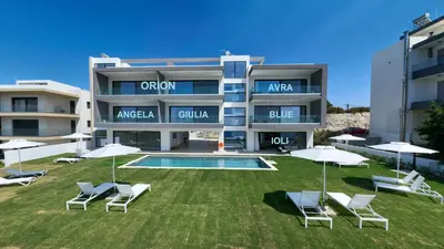 a building with a yard with chairs and umbrellas at Aquarama Pool Apt. - Blue in Ixia