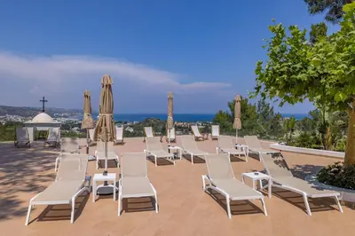a group of chairs and umbrellas on a patio at Aegean View Estate - Villa in Faliraki
