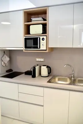 a kitchen with white cabinets and a microwave at KOUROS STONE SUITES in Haraki