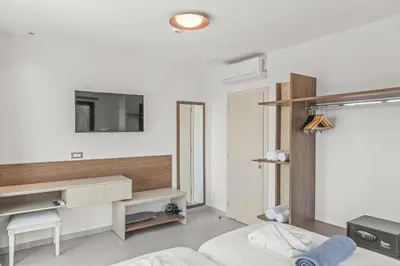 a white bedroom with a bed and a desk at KOUROS STONE SUITES in Haraki
