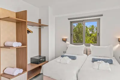 two beds in a room with a window at KOUROS STONE SUITES in Haraki