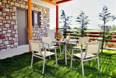 a patio with a table and chairs on the grass at KOUROS STONE SUITES in Haraki