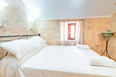 a bedroom with a bed with white sheets and a window at EIRINI in Symi