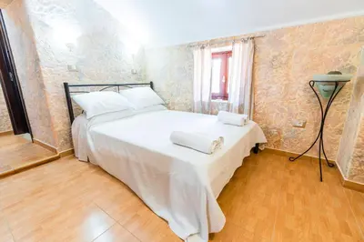 a bedroom with a bed with white sheets and a window at EIRINI in Symi