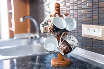 a group of coffee mugs on a wooden stand next to a sink at EIRINI in Symi
