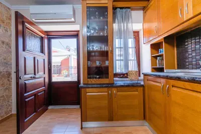 a kitchen with wooden cabinets and a door with a window at EIRINI in Symi