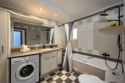 a bathroom with a washing machine and a bath tub at Aelia Luxury Villa in Sálakos